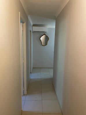 A narrow hallway with a tiled floor, a white door on the left, and a wall-mounted air conditioning unit. - 150-square-meter vacation home in Saint-Rémy-de-Provence, with a large garden and a pool (Saint-Rémy-de-Provence)