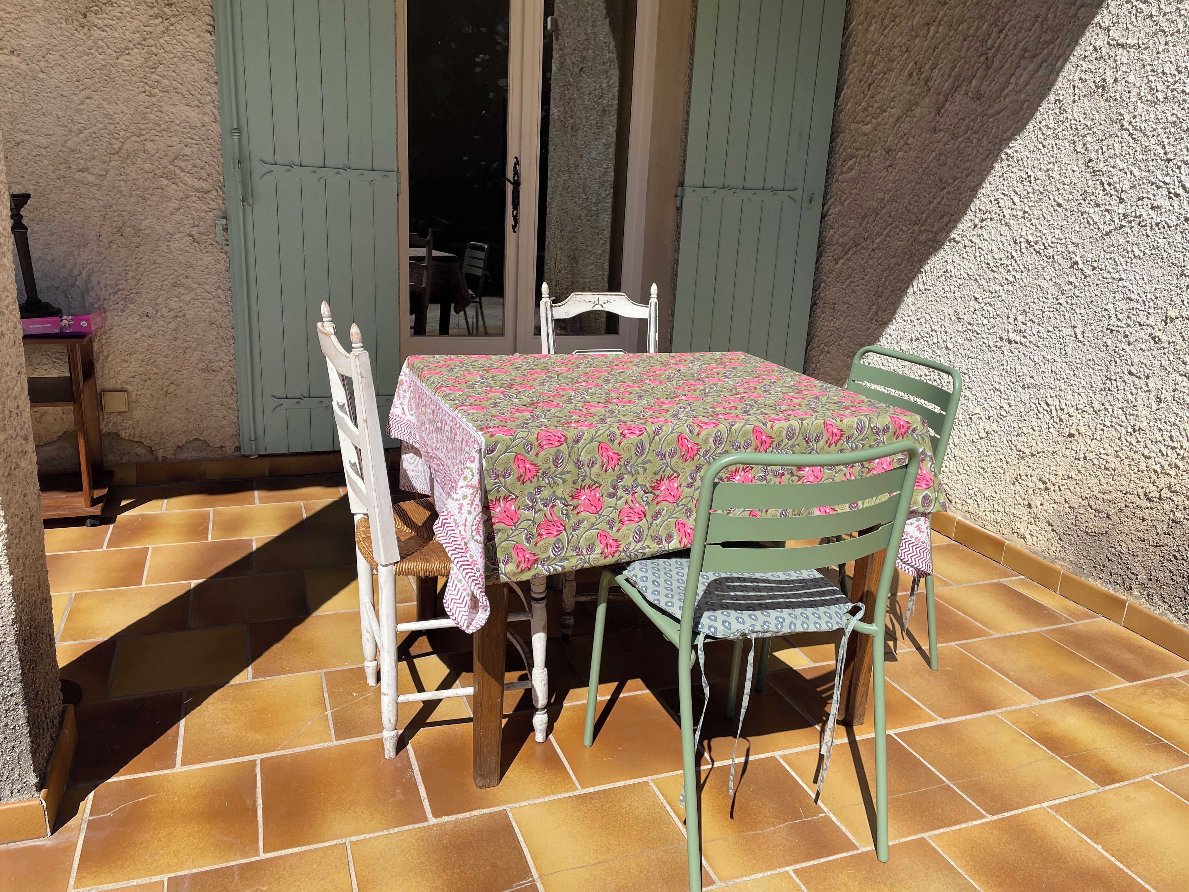 A patio with a table and chairs, a door, and a wall.