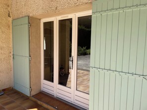 A sliding glass door with a metal gate, a tiled patio, and a small garden area visible through the door. - 150-square-meter vacation home in Saint-Rémy-de-Provence, with a large garden and a pool (Saint-Rémy-de-Provence)