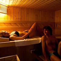 Interior de una cabaña de madera con una cama y un banco.