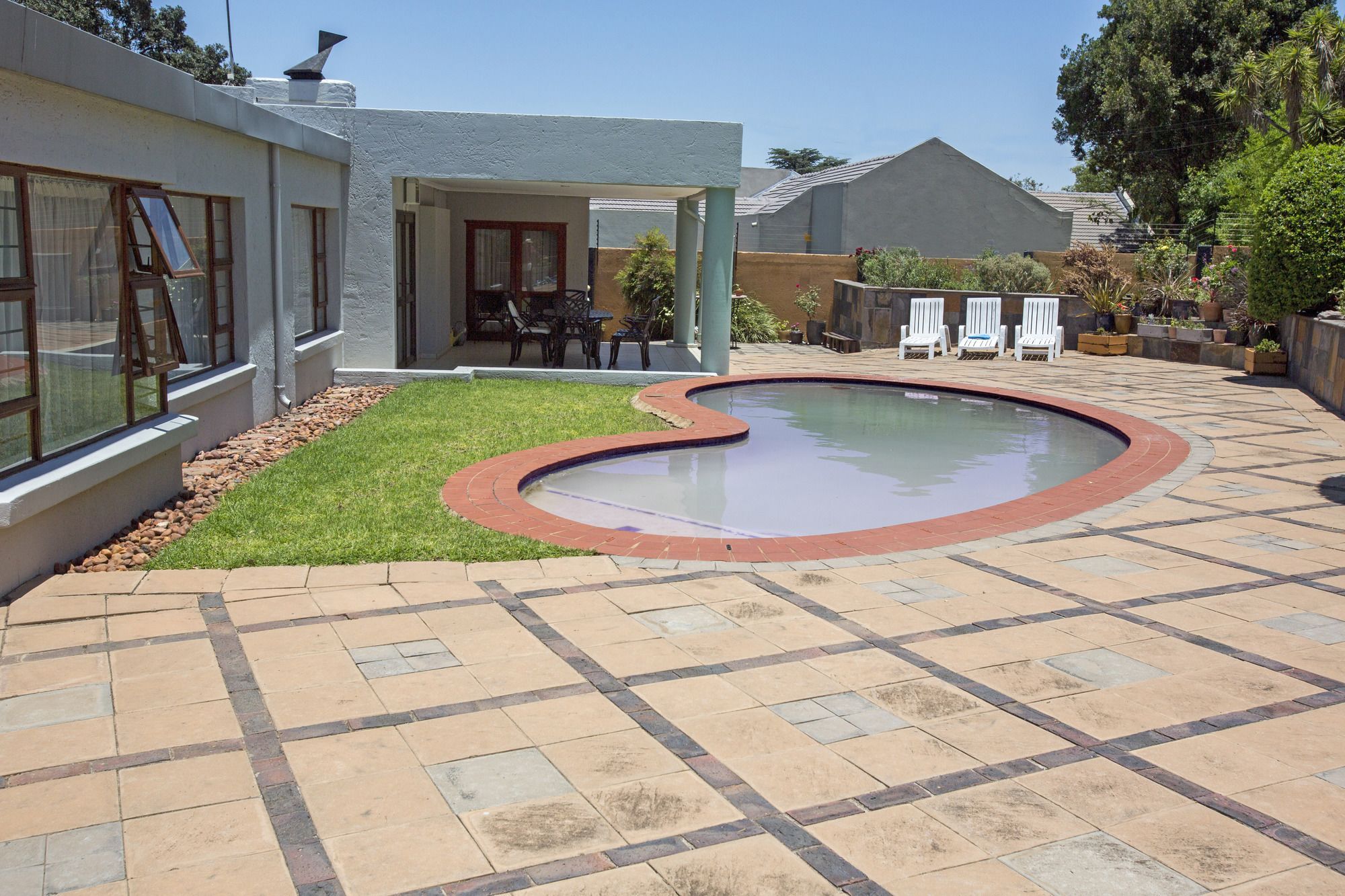 Una piscina a forma curva, circondata da un patio con piastrelle decorate.