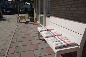 Een bank met kussens, een hond en een bakstenen muur.