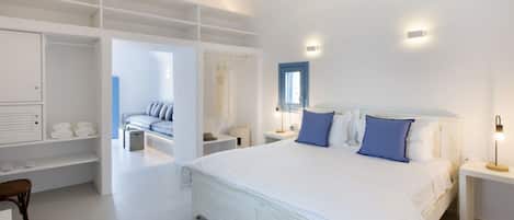 Un dormitorio con una cama grande, mesitas de noche, un armario y una zona de estar con un sofá y sillones.
