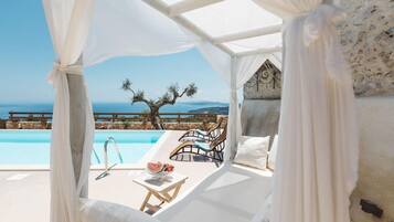 A private pool area with a canopy, lounge chairs, and a view of the sea.
