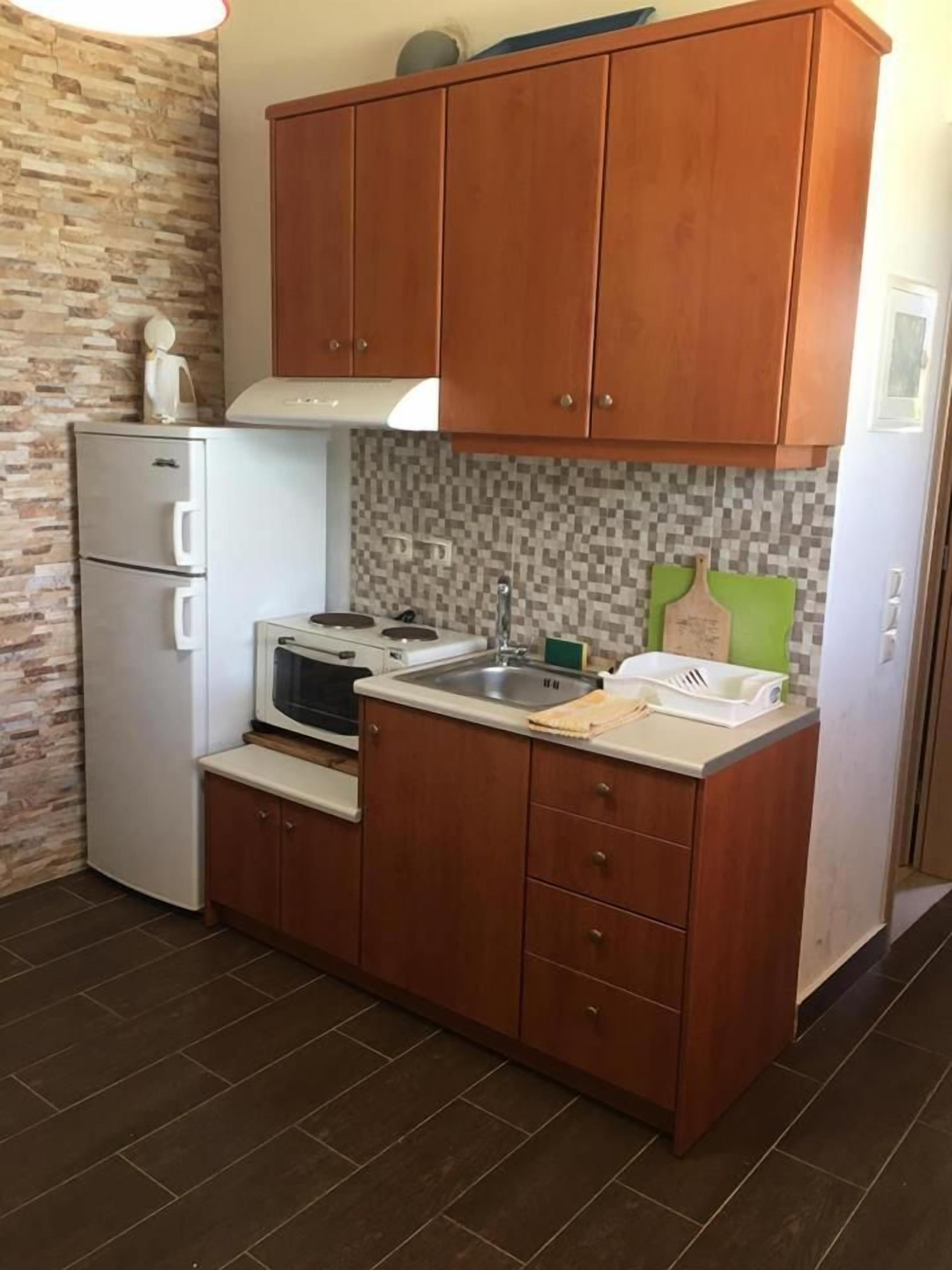 A compact kitchen with wooden cabinets, a white refrigerator, a microwave, and a stove.