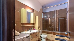 Un baño moderno con lavadora integrada, inodoro, lavabo y cabina de ducha.