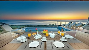 Una mesa de desayuno lista, con vista al océano y al atardecer.