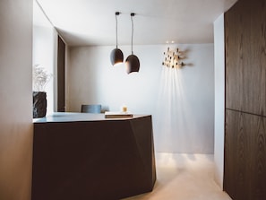 Ein moderner Empfangstresen mit dunkler Arbeitsplatte, ein Stuhl und ein Buch mit dem Titel "The Design Hotels' Book".