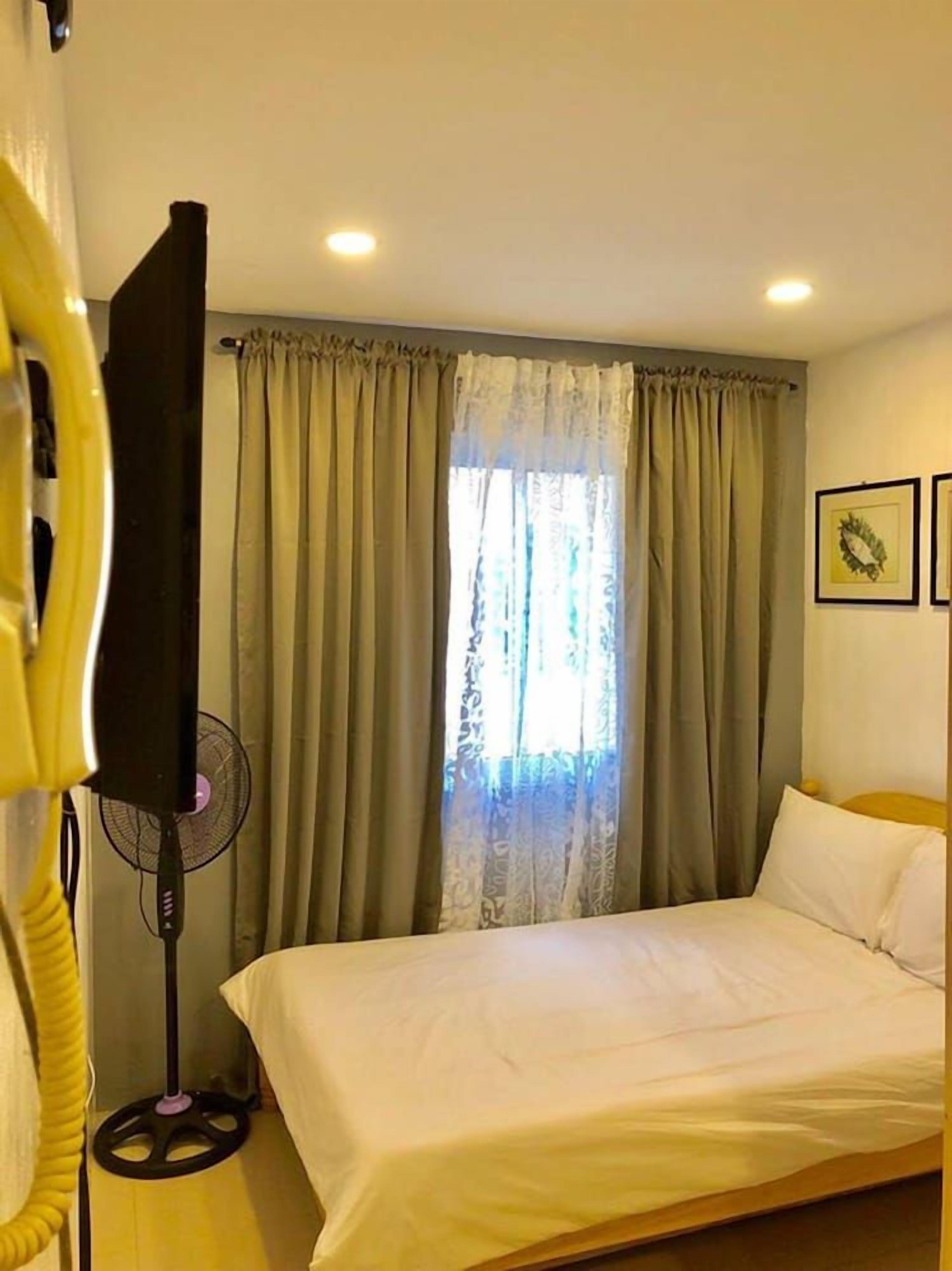 Una habitación de hotel con una cama, cortinas, un ventilador y una televisión.