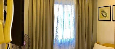 Una habitación de hotel con una cama, cortinas, un ventilador y una televisión.