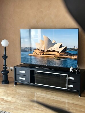 A flat-screen TV mounted on a black entertainment center with a Sydney Opera House image displayed. - Spacious 3 bedrooms Apartment in Sydney CBD /2 Full bathrooms (Sydney)