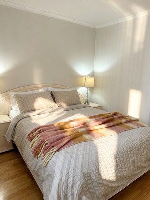 Et soveværelse med en seng, et natbord, en lampe og et vindue.
