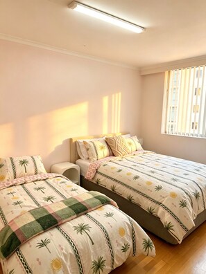 A bedroom with two beds, a nightstand, and a window with blinds. - Spacious 3 bedrooms Apartment in Sydney CBD /2 Full bathrooms (Sydney)