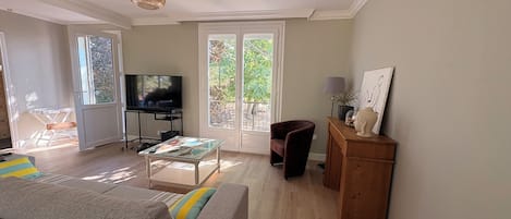 Ein Wohnzimmer mit einer Couch, einem Fernseher, einem Couchtisch und einem Schrank.