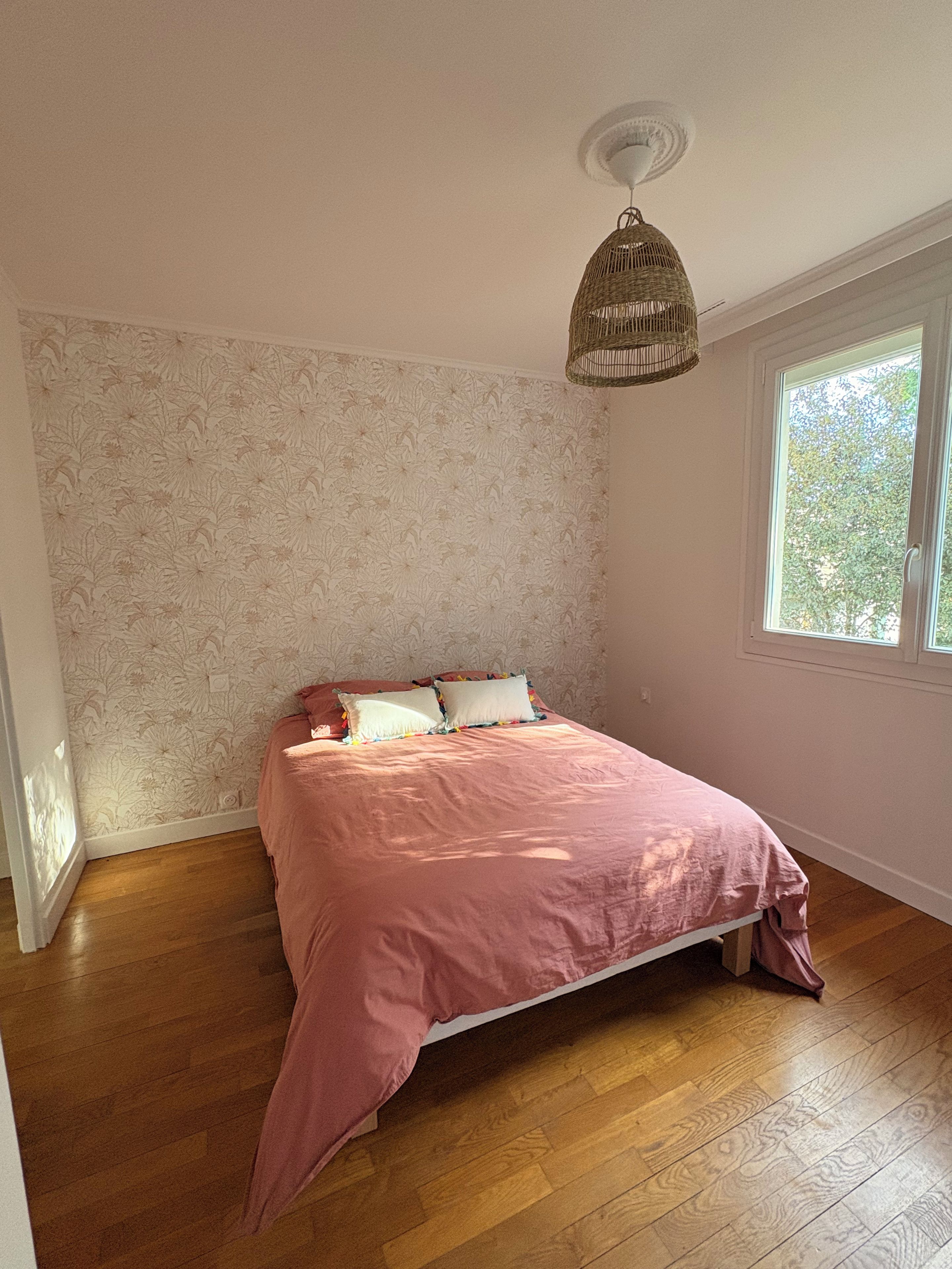 Une chambre à coucher avec un lit, une fenêtre et un luminaire au plafond.