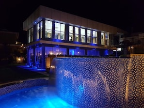 Un hotel moderno con zona de piscina, ventanas iluminadas y un muro de piscina a cuadros.