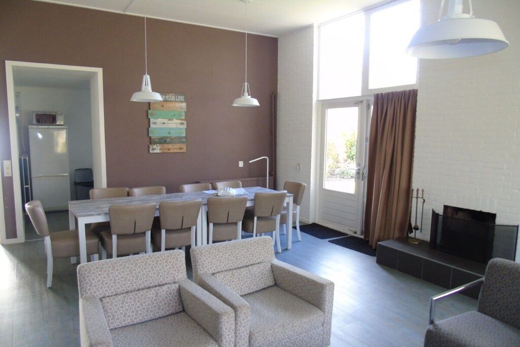 Ein modernes Wohnzimmer mit Essbereich, Kamin und Blick durch ein großes Fenster.