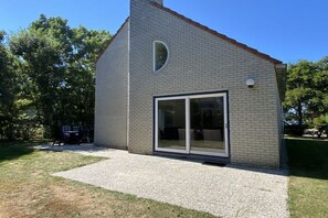 A modern building with a brick exterior, a large glass door, and a small window. - Holiday home with 1 bedroom (Julianadorp)