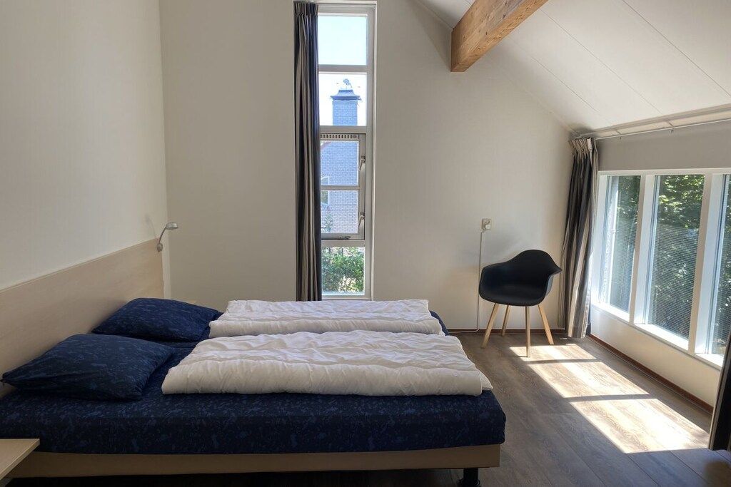 Een slaapkamer met een bed, een stoel en een raam.