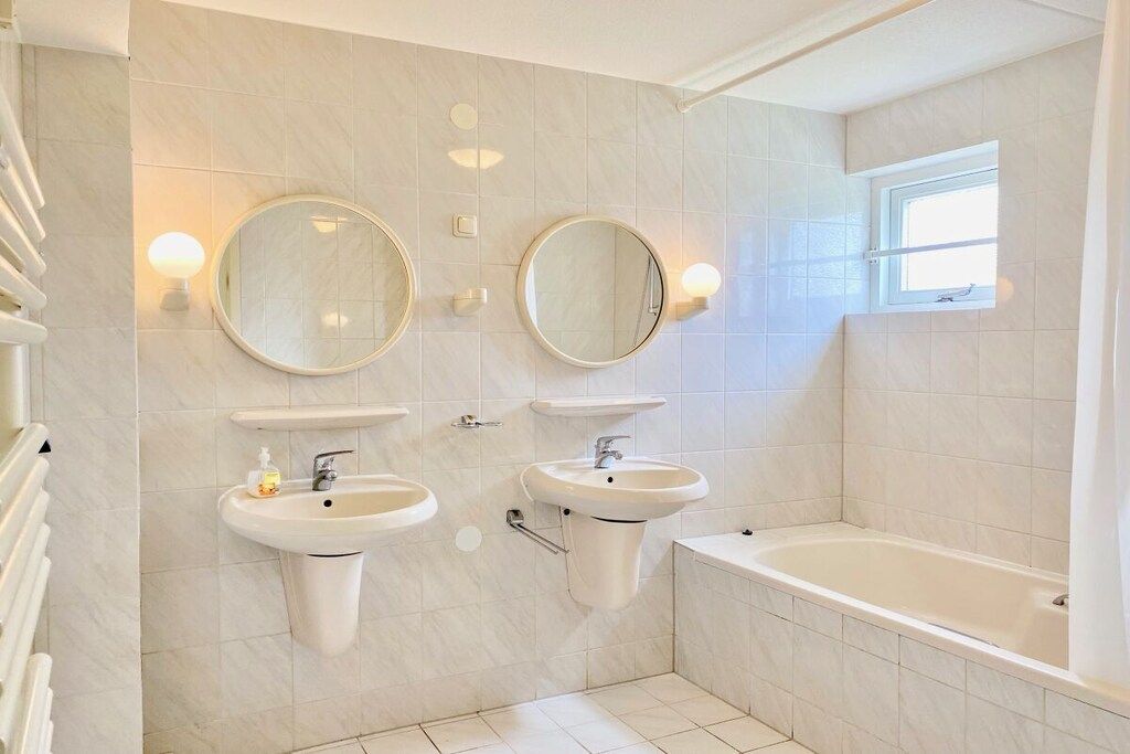 Un bagno con due lavandini, due specchi, una vasca e una finestra.