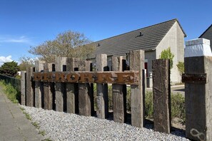 Une enseigne en bois portant le nom « DEKORRE » est placée devant un bâtiment dont le toit est recouvert de tuiles.