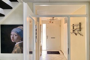 A hallway with a white door, a black doormat, and a wall-mounted metal rack. - Holiday home with 3 bedrooms (Julianadorp aan Zee)