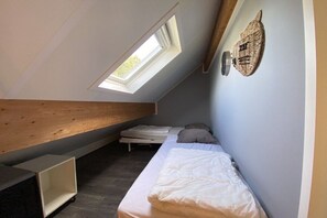 A small, compact room with a sloped ceiling, a single bed, a skylight, and a wooden beam structure. - Holiday home with 3 bedrooms (Julianadorp aan Zee)
