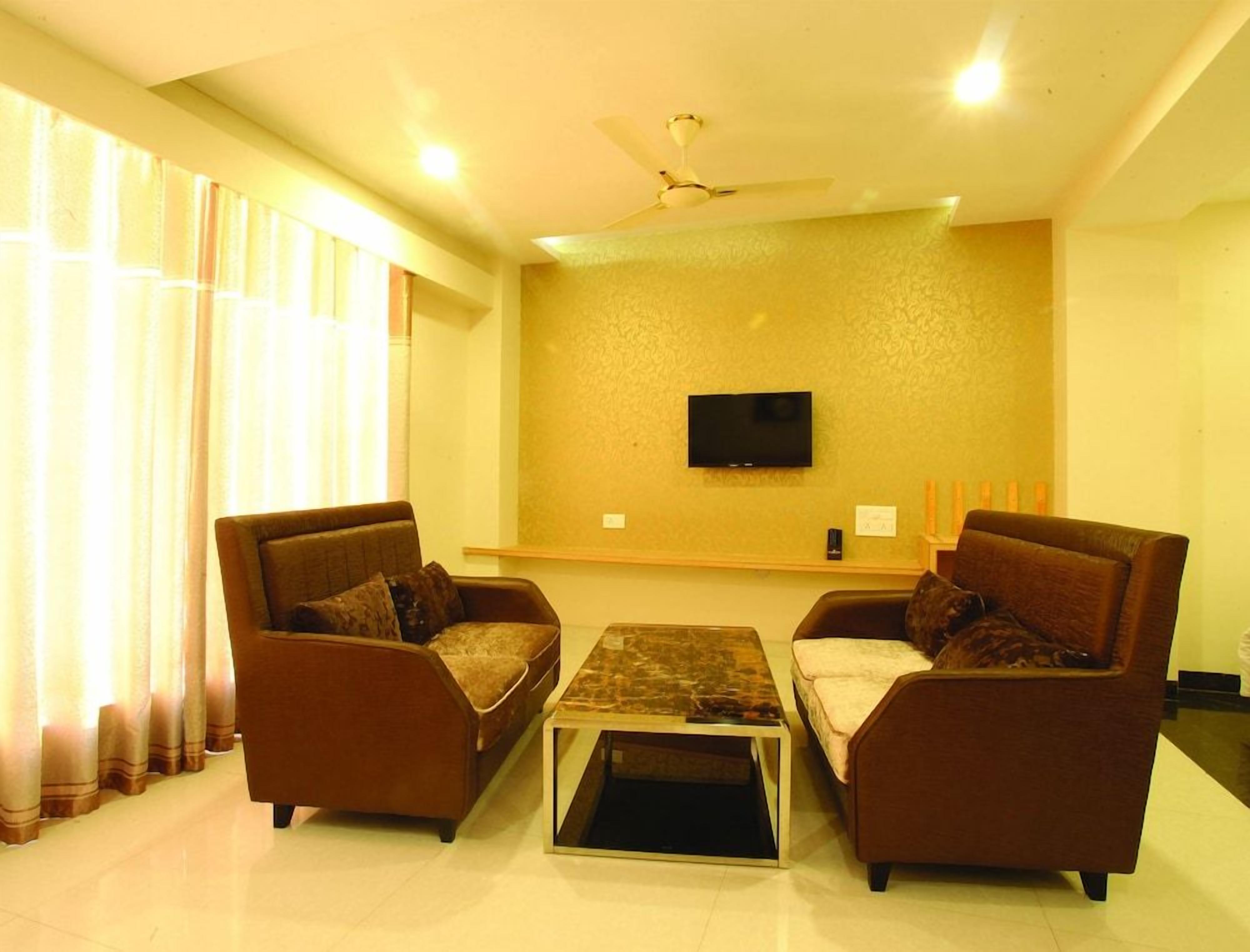 A living room with two sofas, a coffee table, a flat-screen TV on the wall, and a ceiling fan.