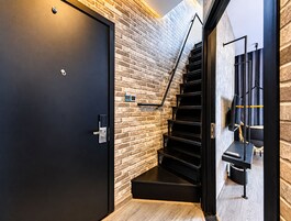 Un interior moderno con una puerta negra, una pared de ladrillo y una escalera.