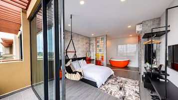 Un dormitorio moderno con una cama grande, una silla colgante, una bañera y un ventanal de vidrio que da a un balcón.