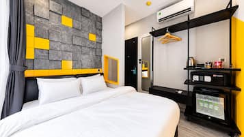 A hotel room with a bed, a wardrobe, a minibar, and a wall-mounted air conditioner.