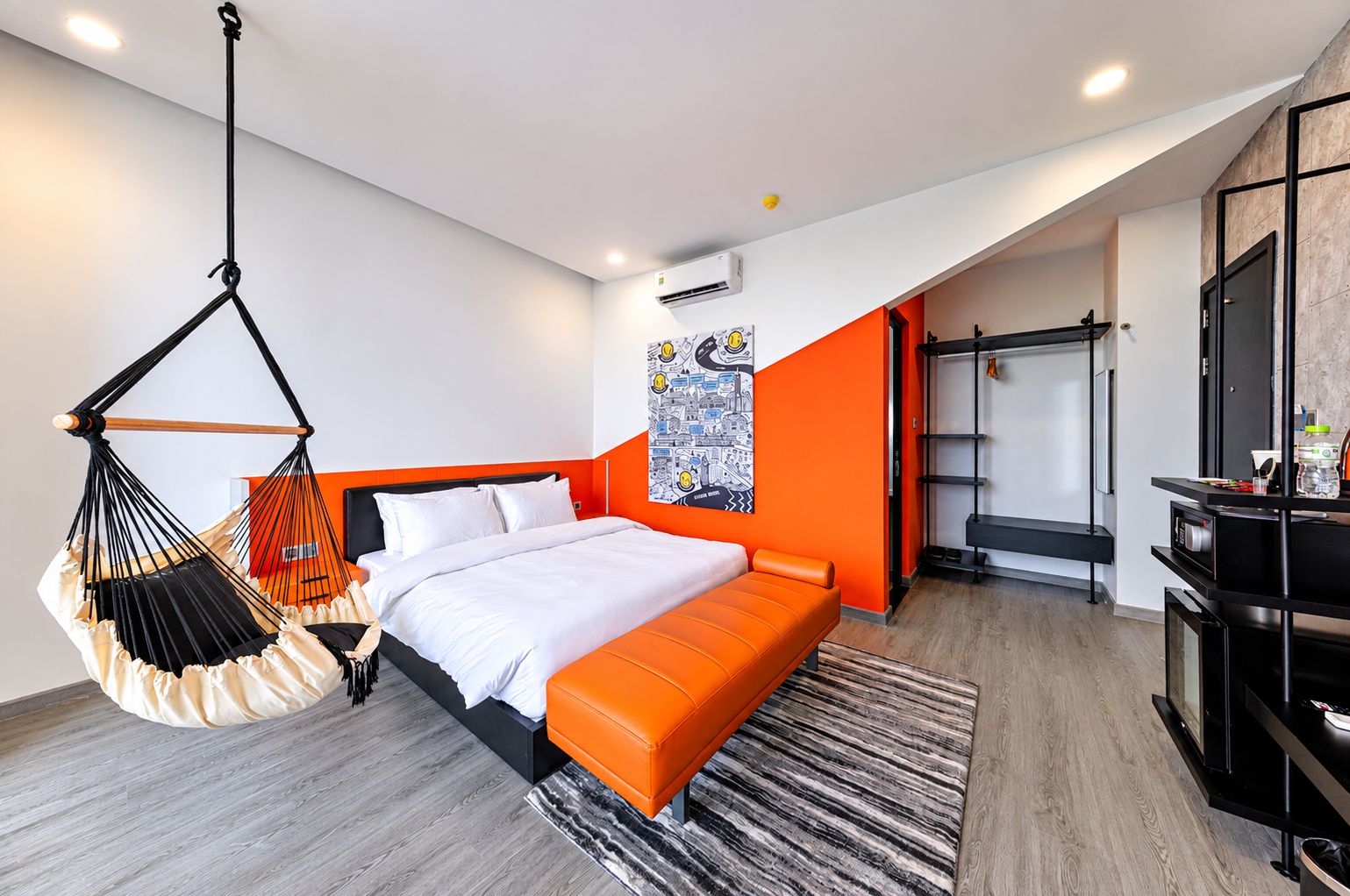 Una habitación de hotel moderna con una cama, una silla colgante, un armario y un escritorio.