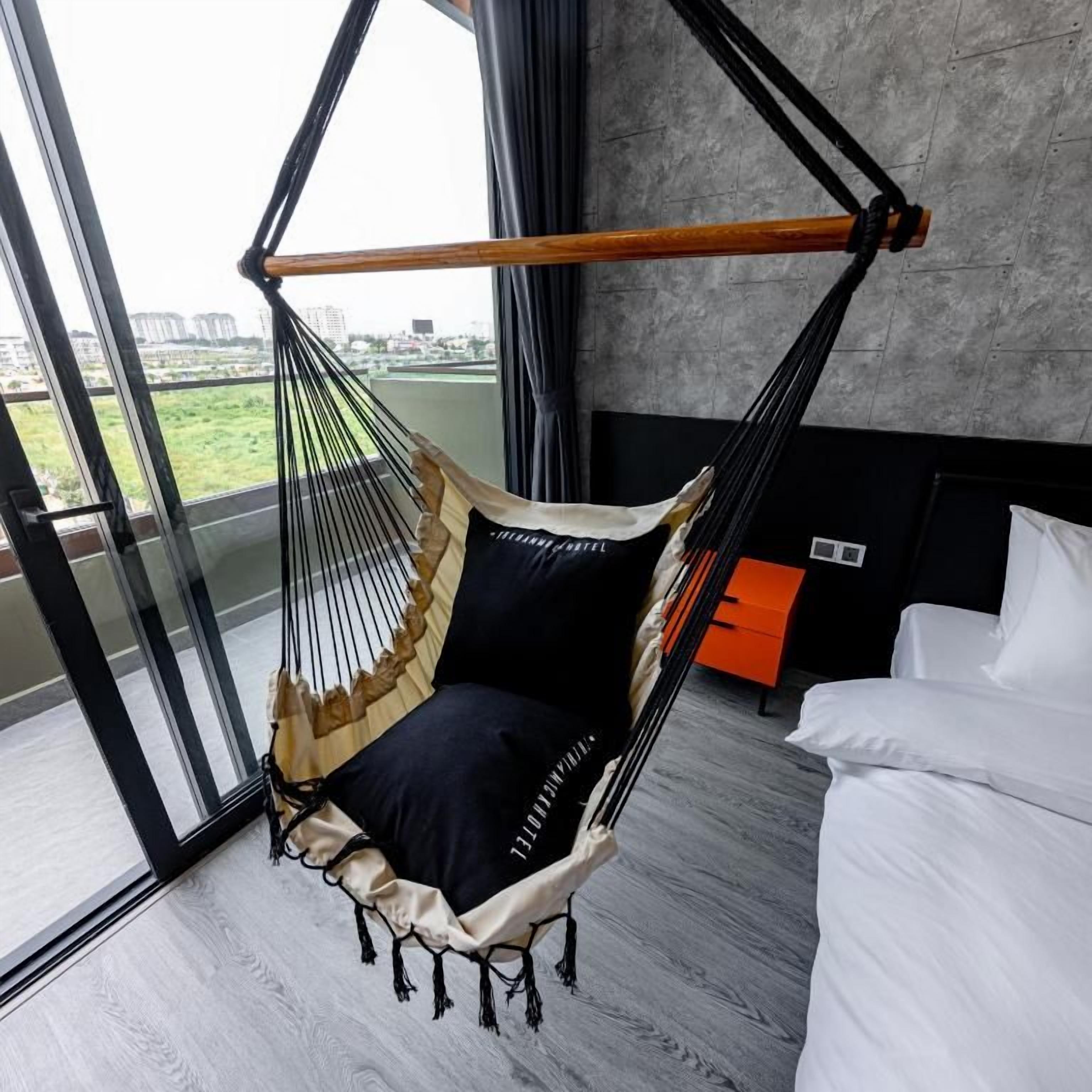 Ein Zimmer mit Hängesessel, Bett und Blick durch eine Glastür.
