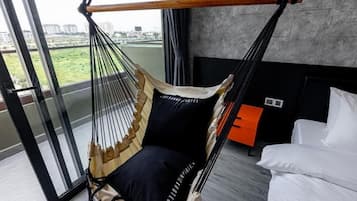 Ein Zimmer mit Hängesessel, Bett und Blick durch eine Glastür.