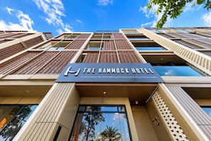 The exterior of The Hammock Hotel with a clear sky, modern architecture, and a prominent sign.