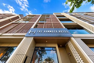 The exterior of The Hammock Hotel with a clear sky, modern architecture, and a prominent sign.