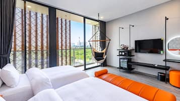 Une chambre d’hôtel moderne avec un grand lit, un canapé, une télévision et une vue sur la ville.
