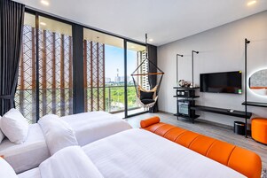 Habitación de hotel moderna con una cama grande, un sofá, un televisor y vistas a la ciudad.