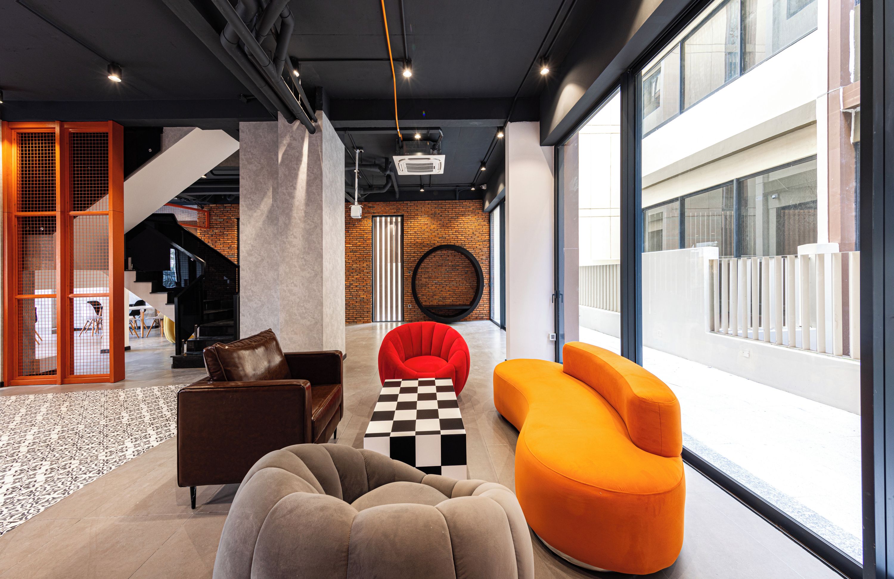 A modern interior with a checkered coffee table, a brown leather sofa, and an orange armchair.