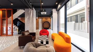 A modern interior with a checkered coffee table, a brown leather sofa, and an orange armchair.