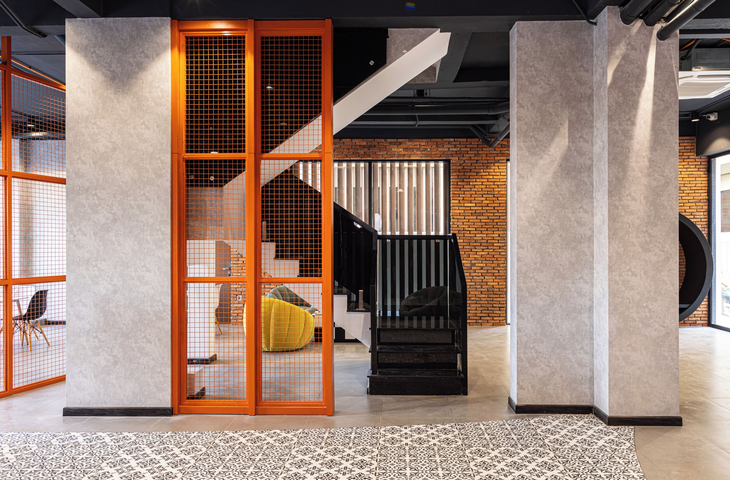 Un interior moderno con una escalera, pared de ladrillo y suelo estampado.