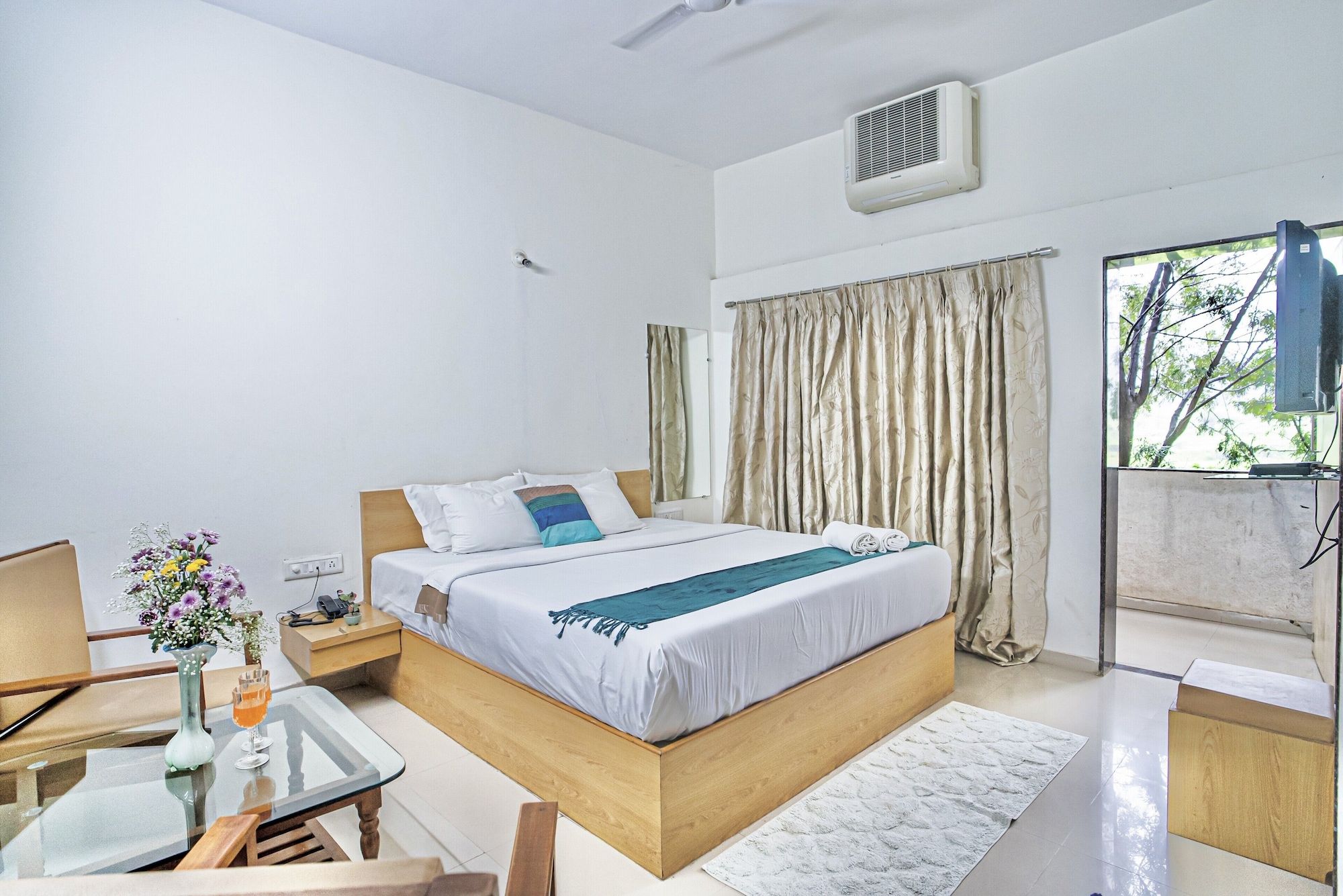 A hotel room with a bed, bedside table, and a window with curtains.