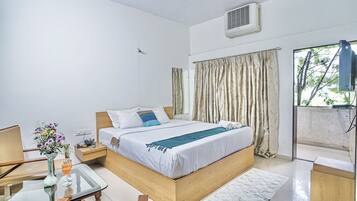 A hotel room with a bed, bedside table, and a window with curtains.