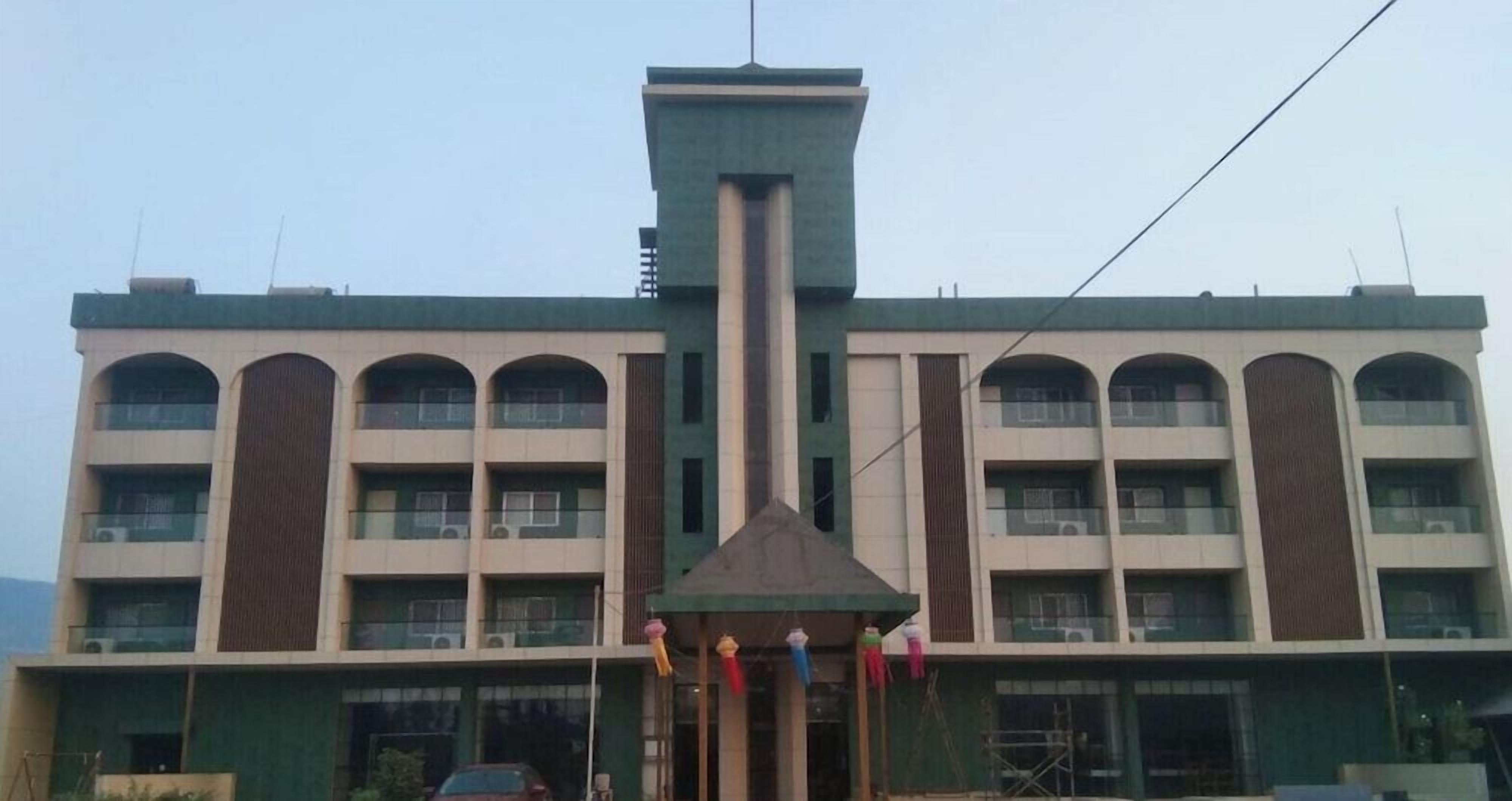 A multi-story building with a central tower, balconies, and a covered entrance.