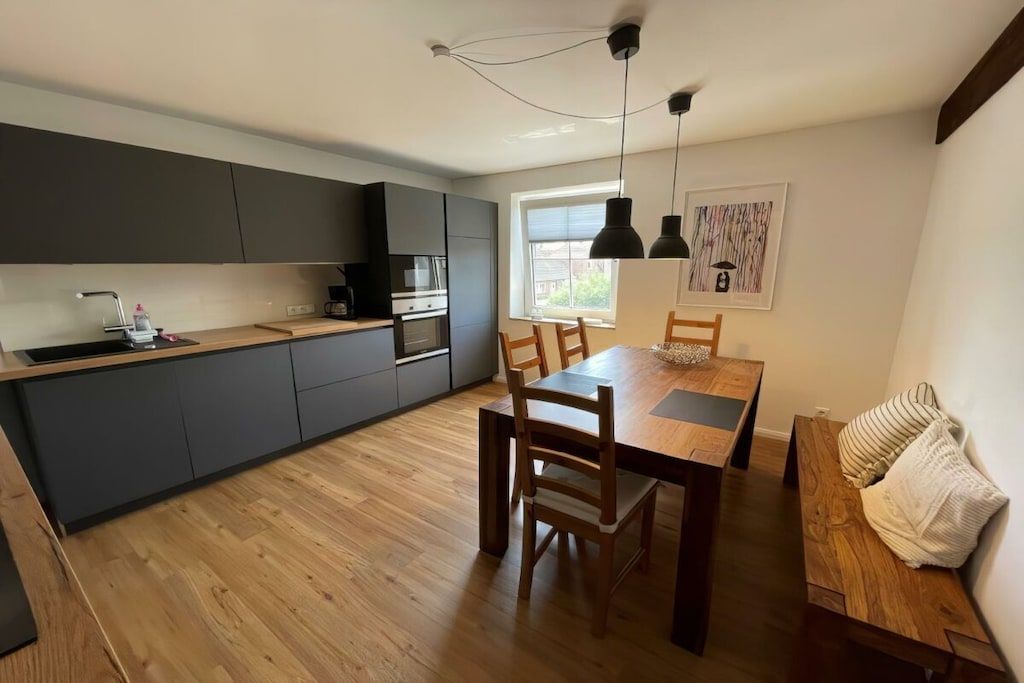 Une cuisine moderne avec des meubles de couleur grise, une table à manger en bois et un banc.