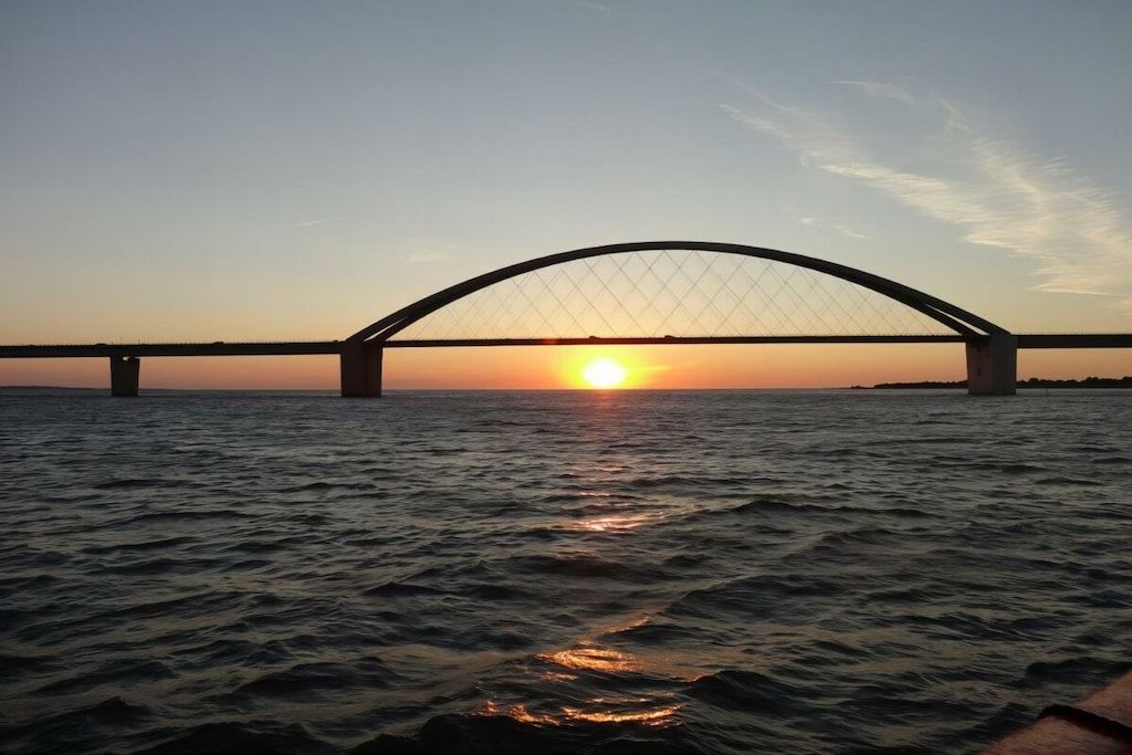 A bridge over water with the sun setting in the background.