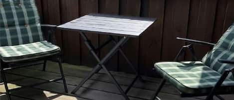 A wooden deck with a table and two chairs.