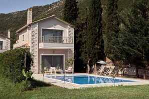 A two-story stone house with a balcony, a swimming pool, and outdoor seating. - Avesta Private Villas Niovi (Lefkada)