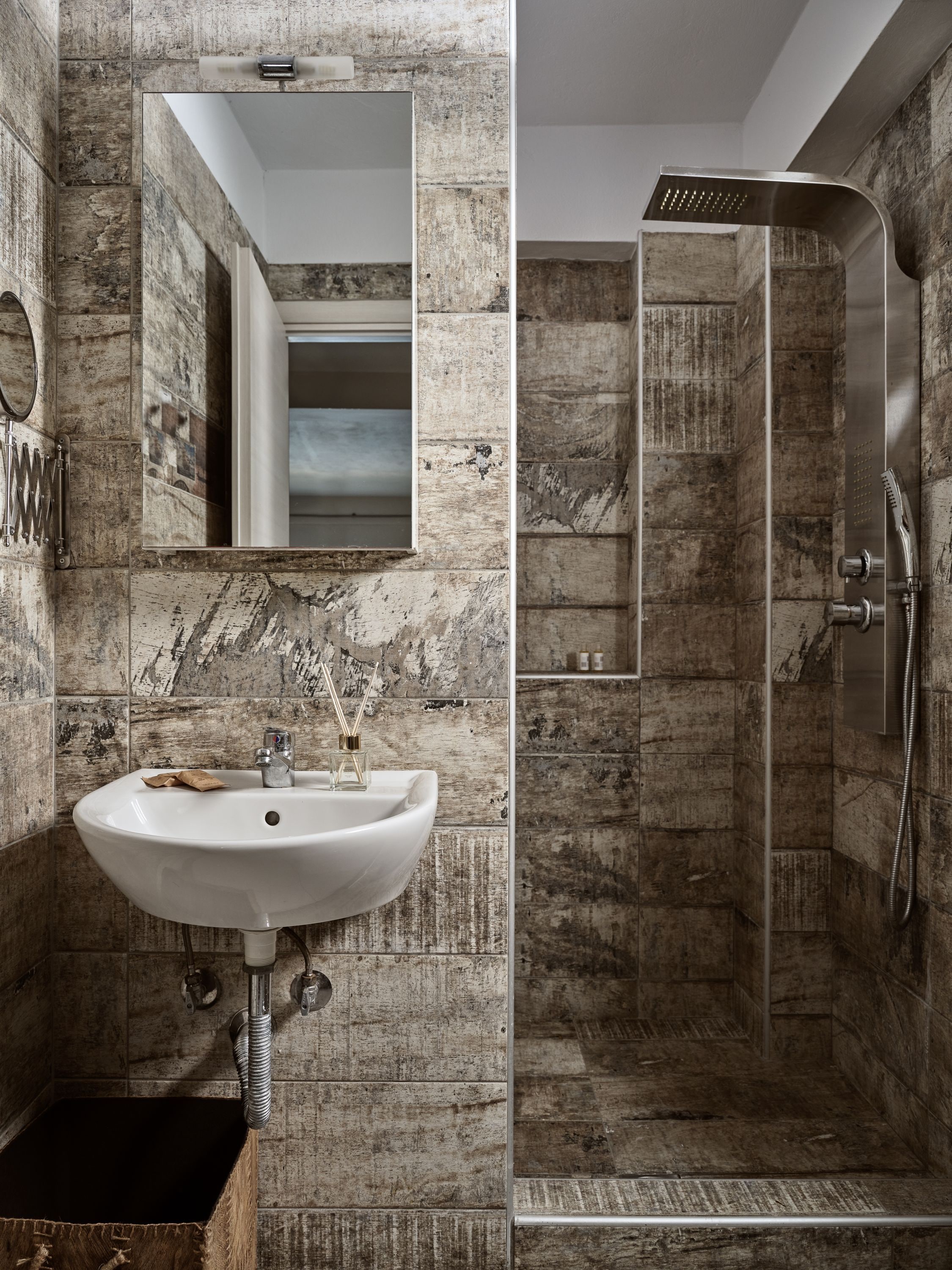 Ein Badezimmer mit Marmorwaschbecken, einem Spiegel und einer Dusche mit einer gebogenen Duschbrause.