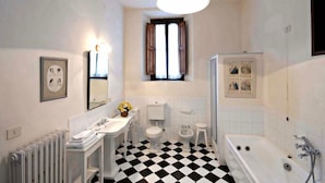 Un baño con piso a cuadros, una bañera, un inodoro, un lavamanos y una ducha.